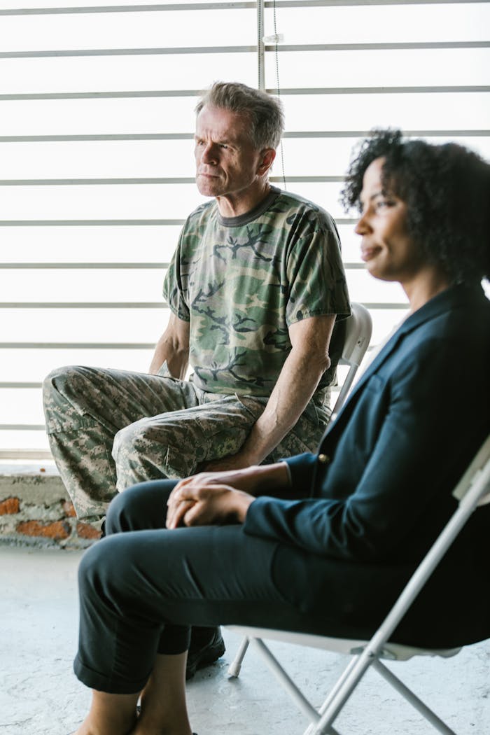 A military veteran in uniform sits with a counselor during a therapy session, promoting mental health.